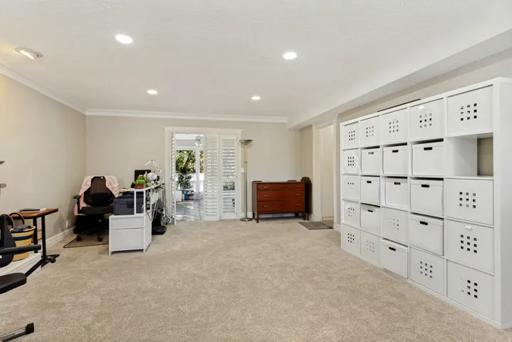 Recessed lighting, crown molding, white bi-fold doors, and built-in white shelving
