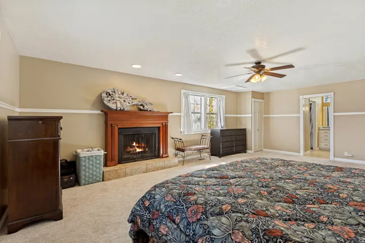 Carpeted room featuring a wood-mantled fireplace with a tile hearth, a ceiling fan with integrated lighting, and recessed ceiling lighting