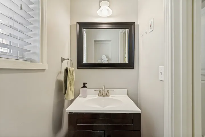 Bathroom featuring a dark wood-finish vanity with an integrated sink, framed mirror, and mounted light fixture