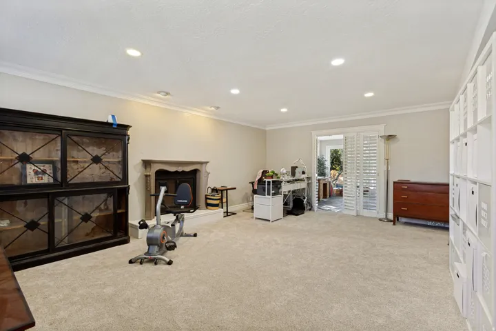 Recessed lighting, crown molding, and a decorative fireplace with a stone surround