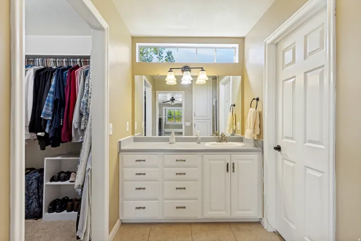 Dual vanity with an integrated countertop, white cabinetry, and a three-light fixture