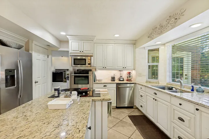 Kitchen featuring white cabinetry, granite countertops, stainless steel appliances, a double basin sink, and recessed lighting