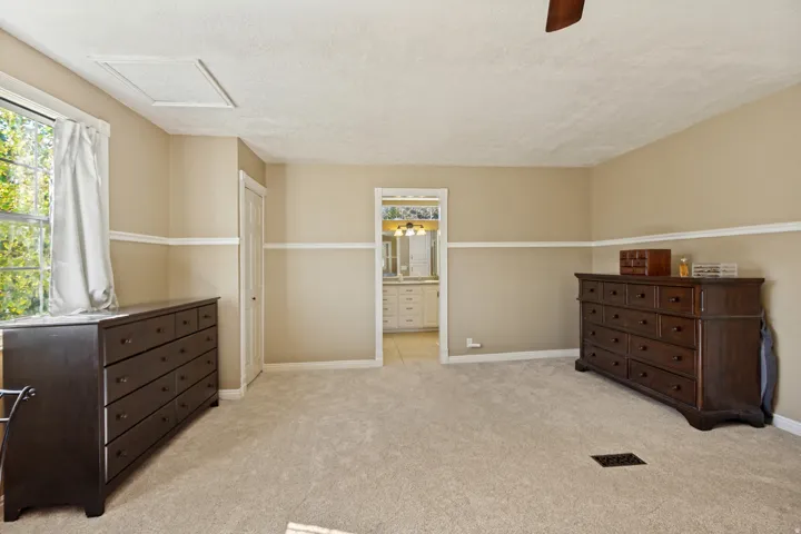 Neutral-toned walls with chair rail molding, light-colored carpet, and a ceiling-mounted fan