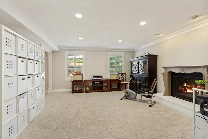 Recessed lighting, crown molding, plantation shutters, and a classic fireplace with a stone surround