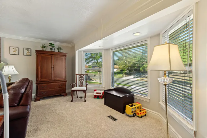 Bay window with multiple panes, recessed ceiling lighting, crown molding, light-colored carpeting, and painted walls