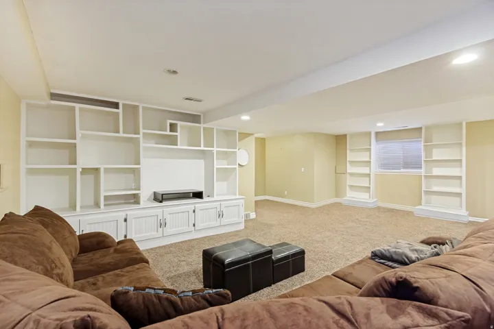 Expansive room featuring recessed lighting, a large built-in media center with open shelving and lower cabinetry, and additional built-in shelving flanking a window