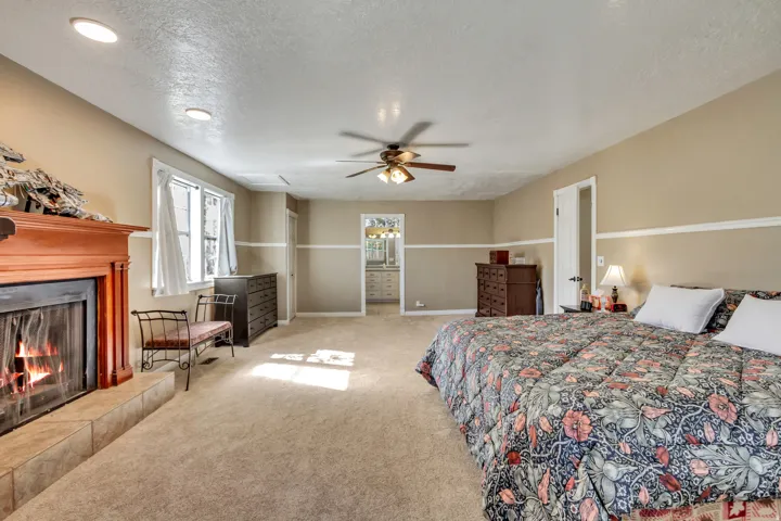 Spacious room featuring a fireplace with a wood-finish mantel and tile surround, recessed lighting, and a ceiling fan