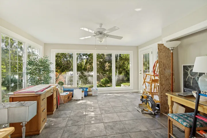 Sunroom featuring tile flooring, a ceiling fan, and multiple large windows with white trim