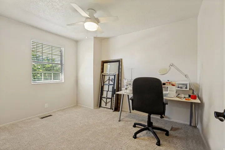 Recessed window with horizontal blinds, overhead ceiling fan with integrated lighting, and neutral tone carpeting