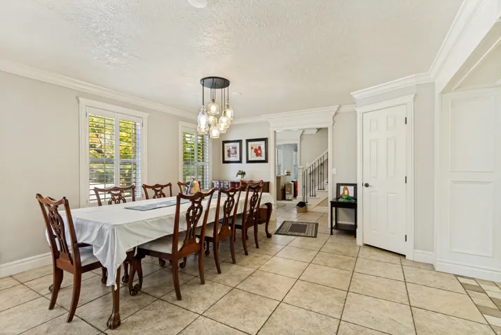 Spacious dining area featuring large windows with white shutters, a contemporary multi-light chandelier, and light-toned tile flooring