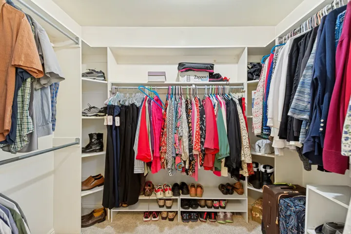 Custom closet system with multiple hanging rods, corner shelving, and integrated shoe storage