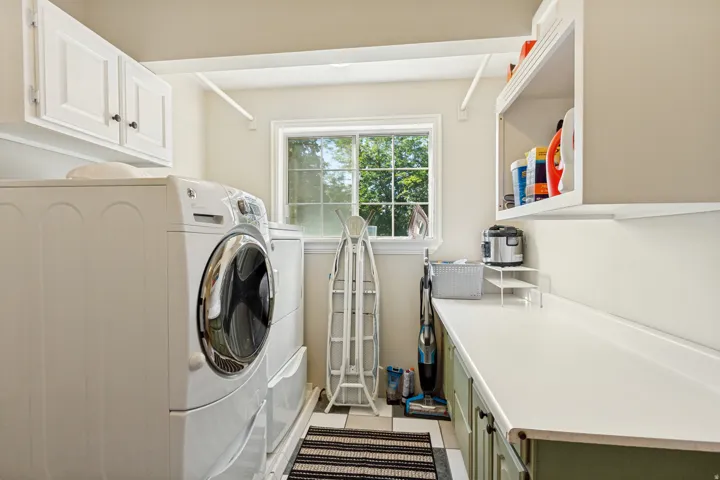 Laundry area featuring white cabinetry, a single window, a light-colored countertop, and a tiled floor
