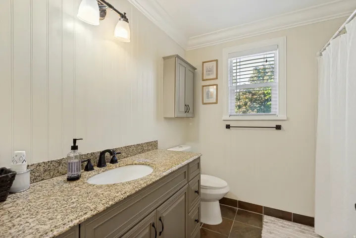 Vanity with granite countertop, integrated sink, and dark-finish faucet