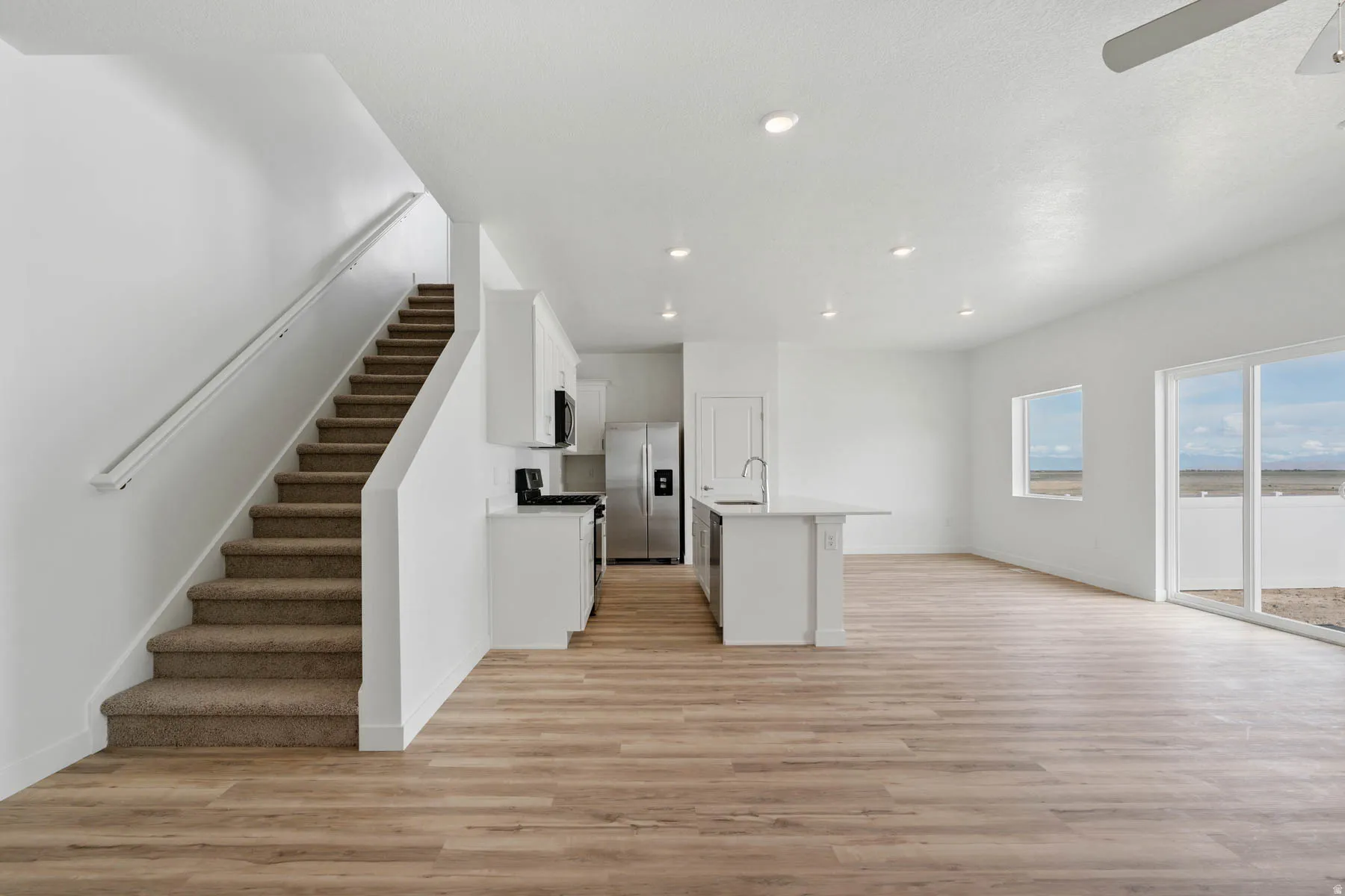 Open-concept living area with wood-finish flooring, recessed lighting, and a white kitchen island