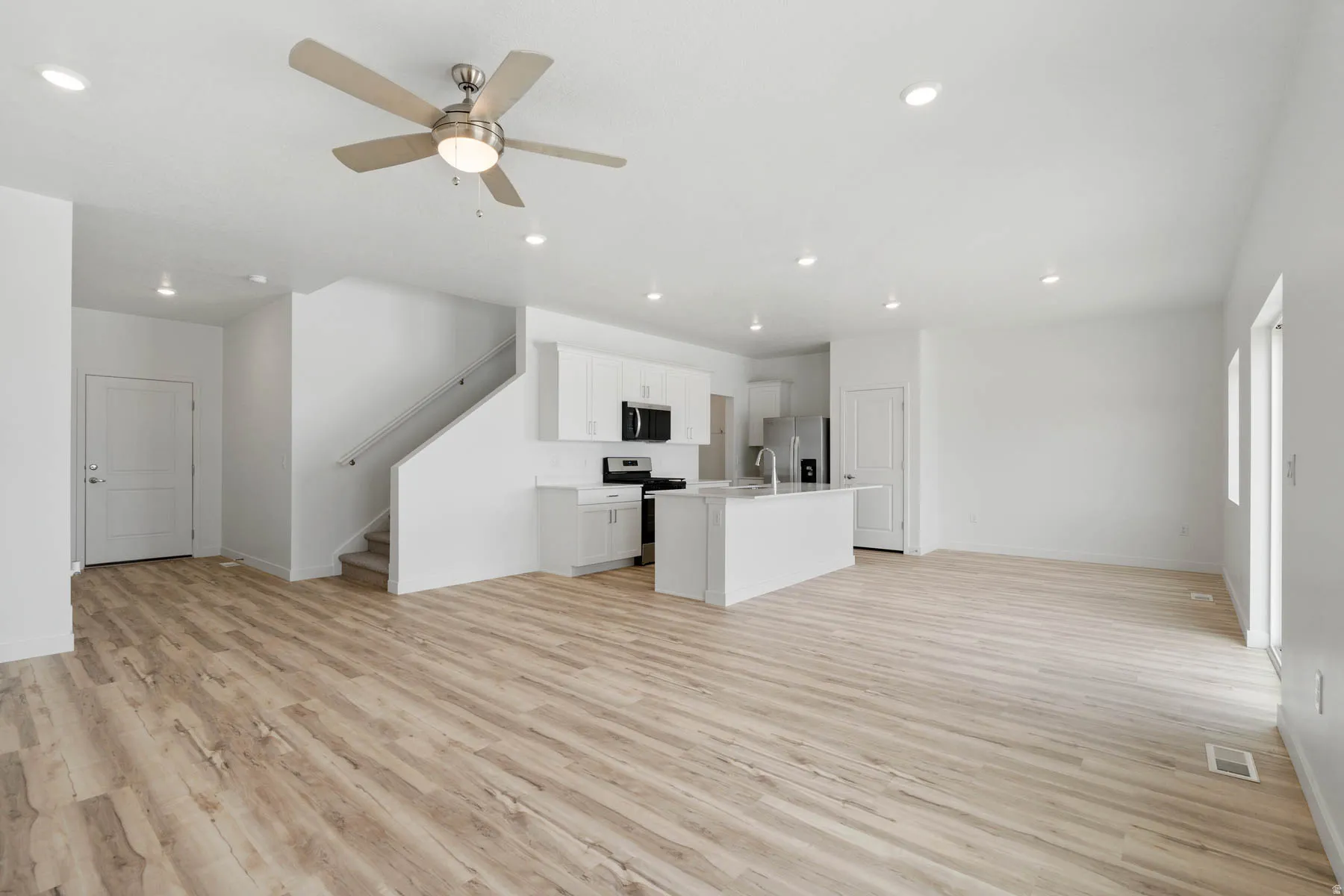 Open-concept living space featuring wood-finish flooring, recessed lighting, and a modern ceiling fan