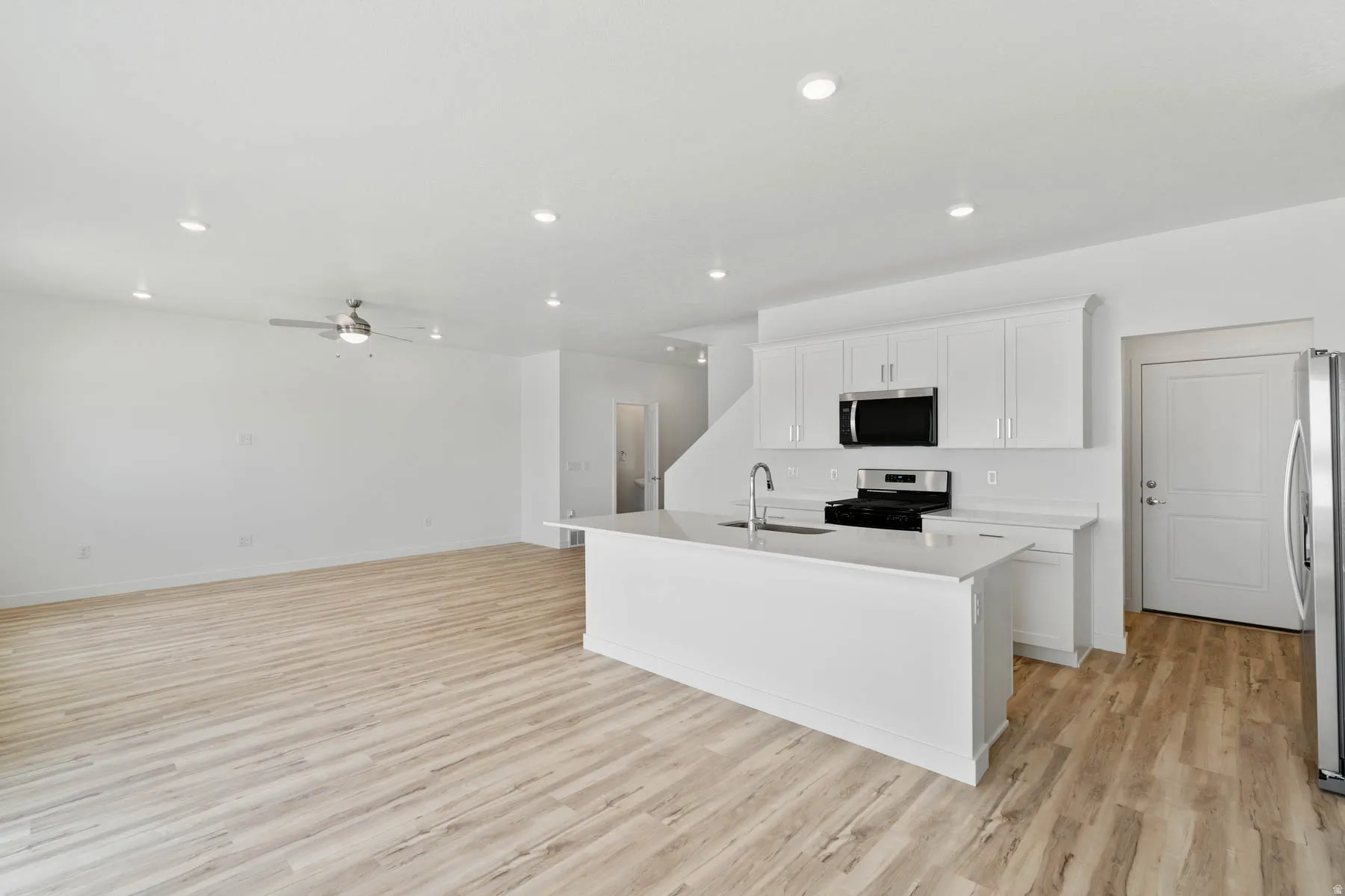 Modern kitchen with white cabinetry, stainless steel appliances, and a central island with a sink