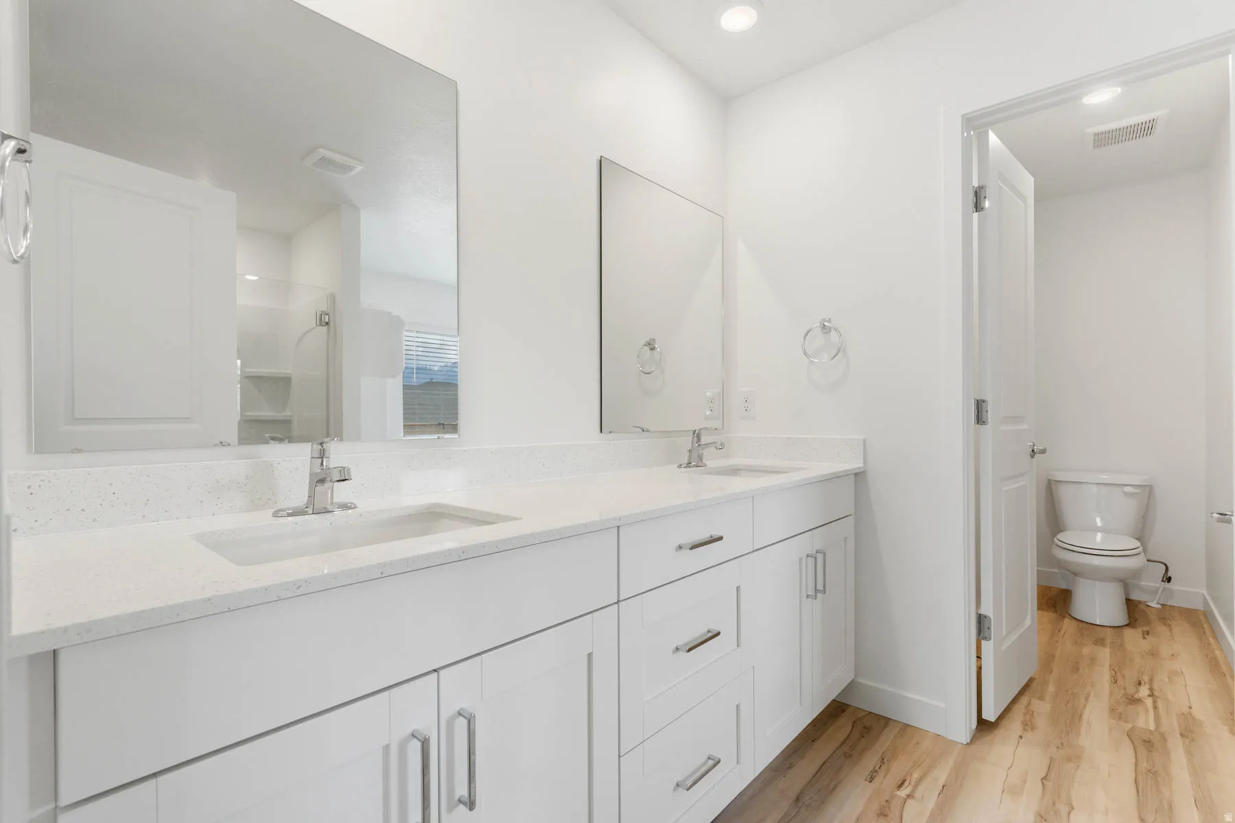 Double vanity with white cabinetry, integrated sinks, chrome fixtures, and a light-toned countertop