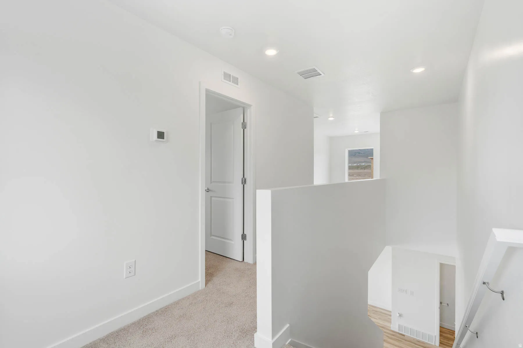 Recessed lighting throughout, white walls, and light-toned carpet flooring