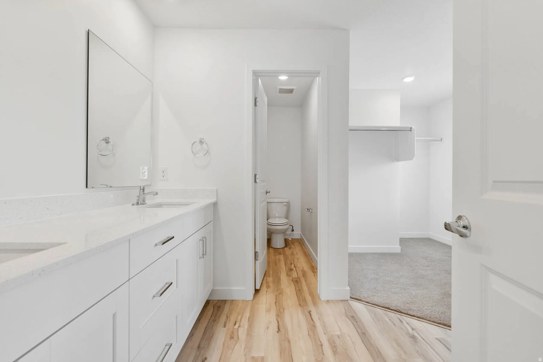 Dual vanity with integrated sinks, white cabinetry, and polished chrome hardware