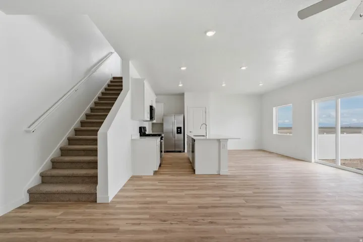 Open-concept living area with wood-finish flooring, recessed lighting, and a white kitchen island