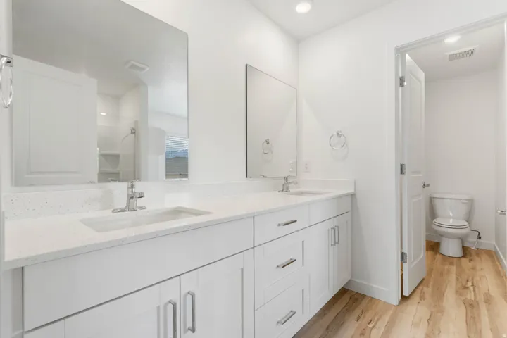 Double vanity with white cabinetry, integrated sinks, chrome fixtures, and a light-toned countertop