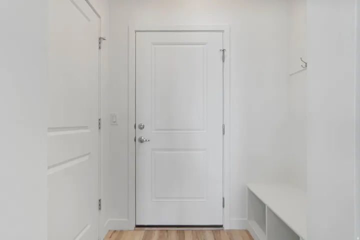 Entryway with wood-finish flooring, a built-in bench with cubby storage, and wall-mounted coat hooks