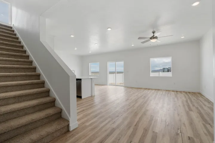 Spacious open-concept living area featuring wood-finish flooring, recessed lighting, and a ceiling fan