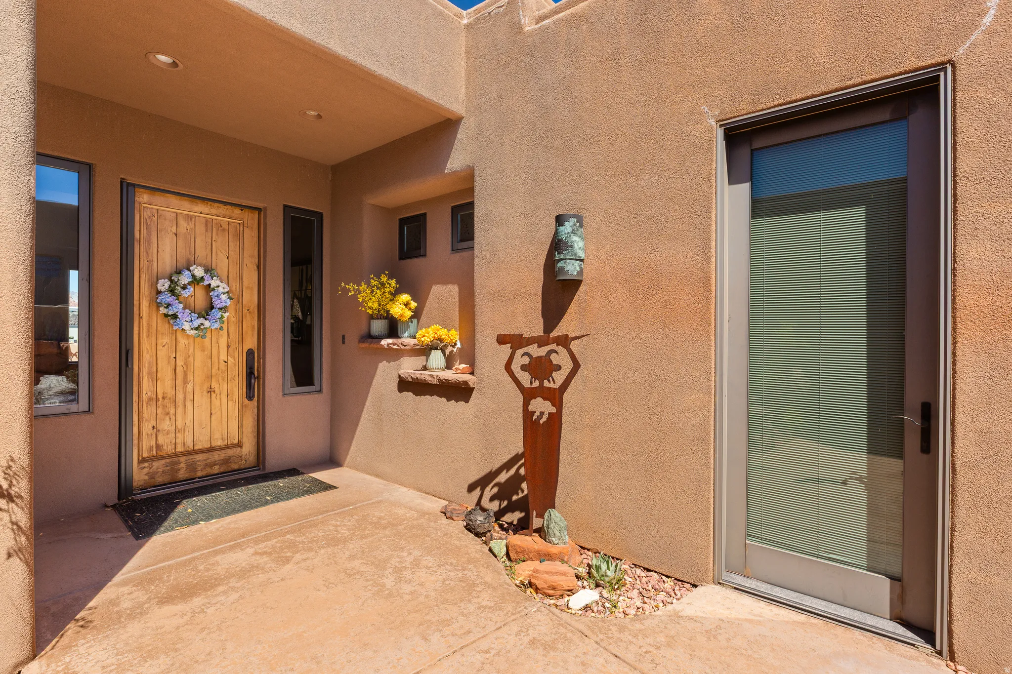 Stucco exterior with a solid wood entry door, adjacent sidelight windows, and a recessed entryway