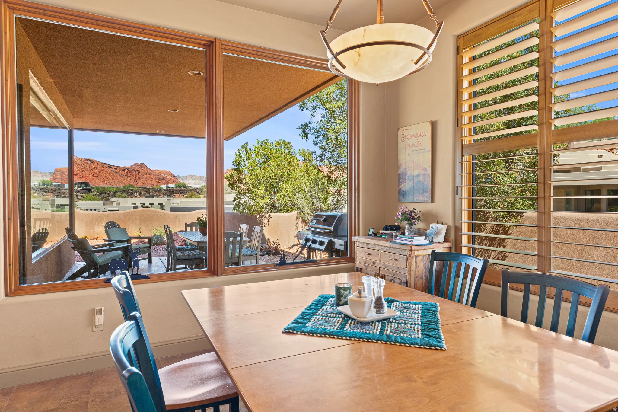 Expansive windows with wood trim, wood plantation shutters, a built-in buffet, and a ceiling-mounted light fixture