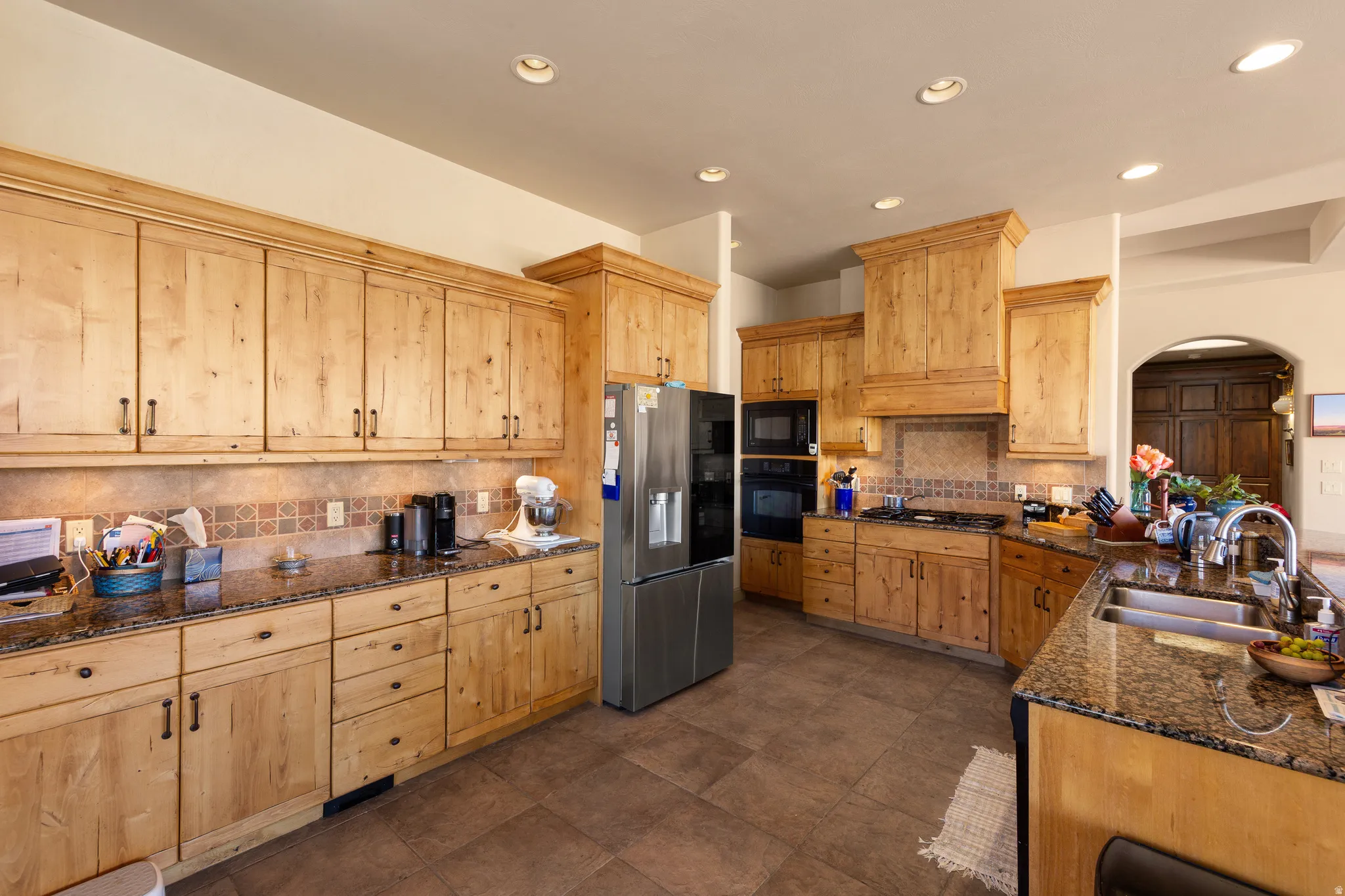 Kitchen featuring extensive wood cabinetry, recessed lighting, tile flooring, and integrated stainless steel appliances