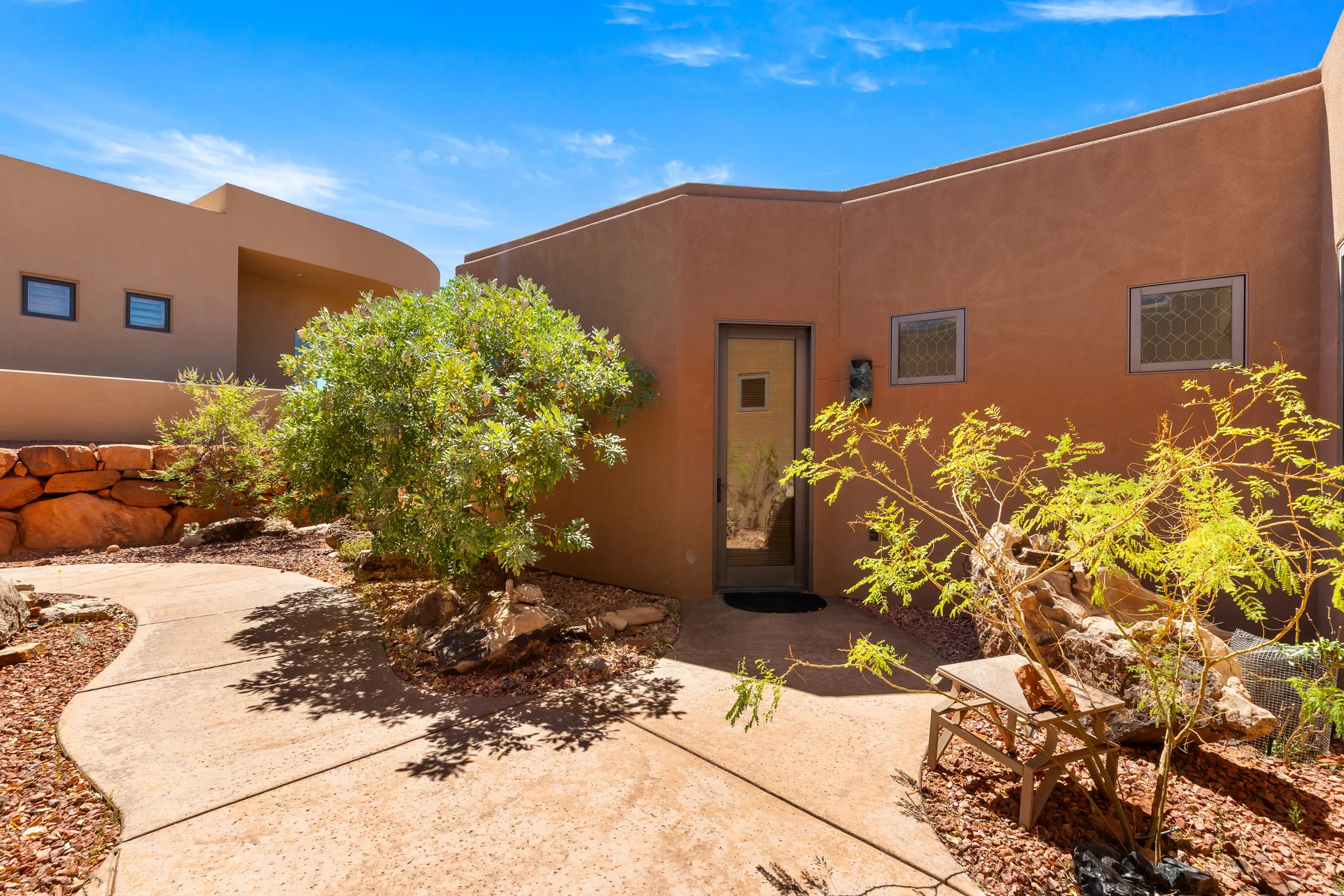 Stucco exterior with a modern entry door, decorative windows, and a curved concrete pathway