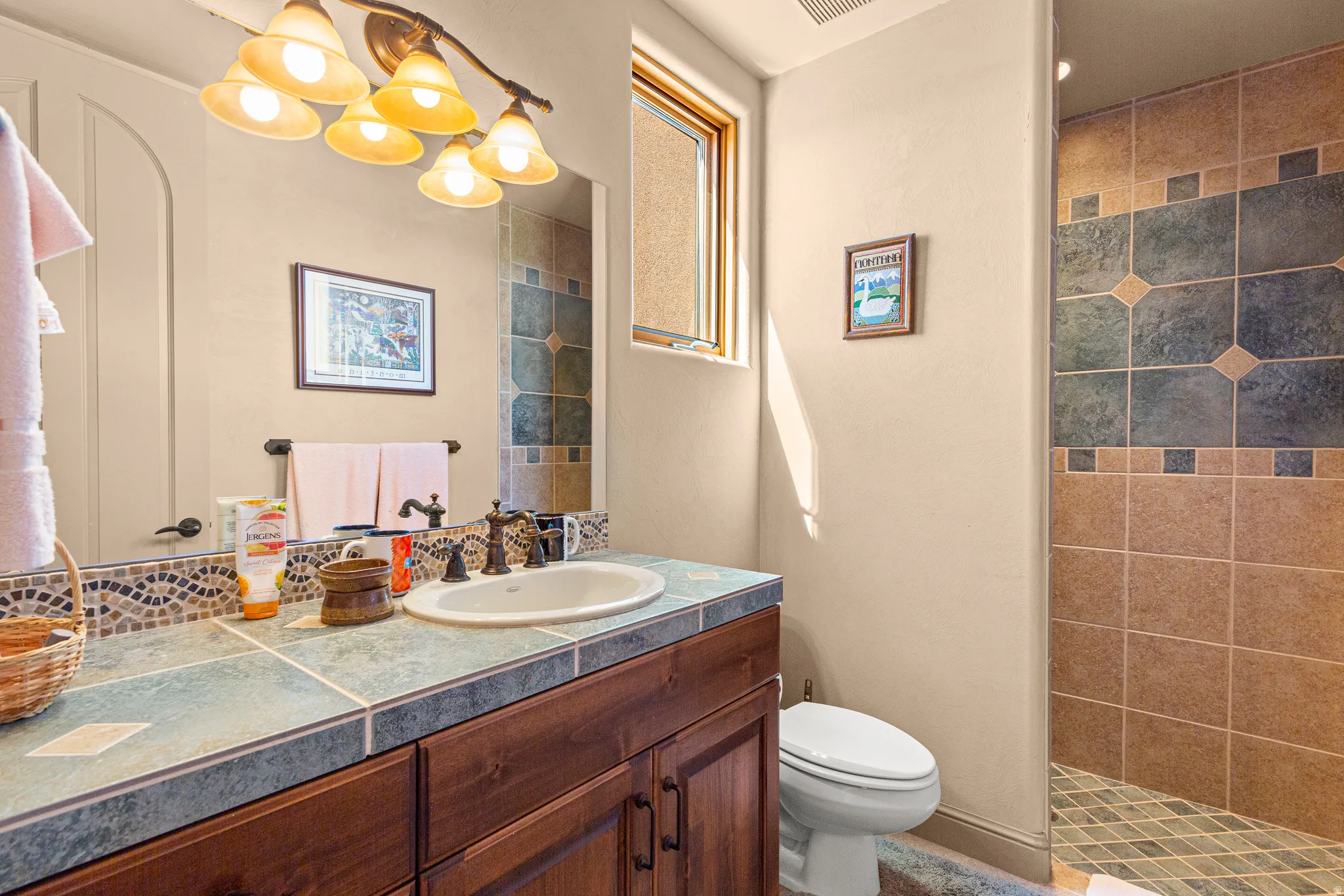 Wood-finish vanity with an integrated sink, tile countertop, and mosaic tile backsplash