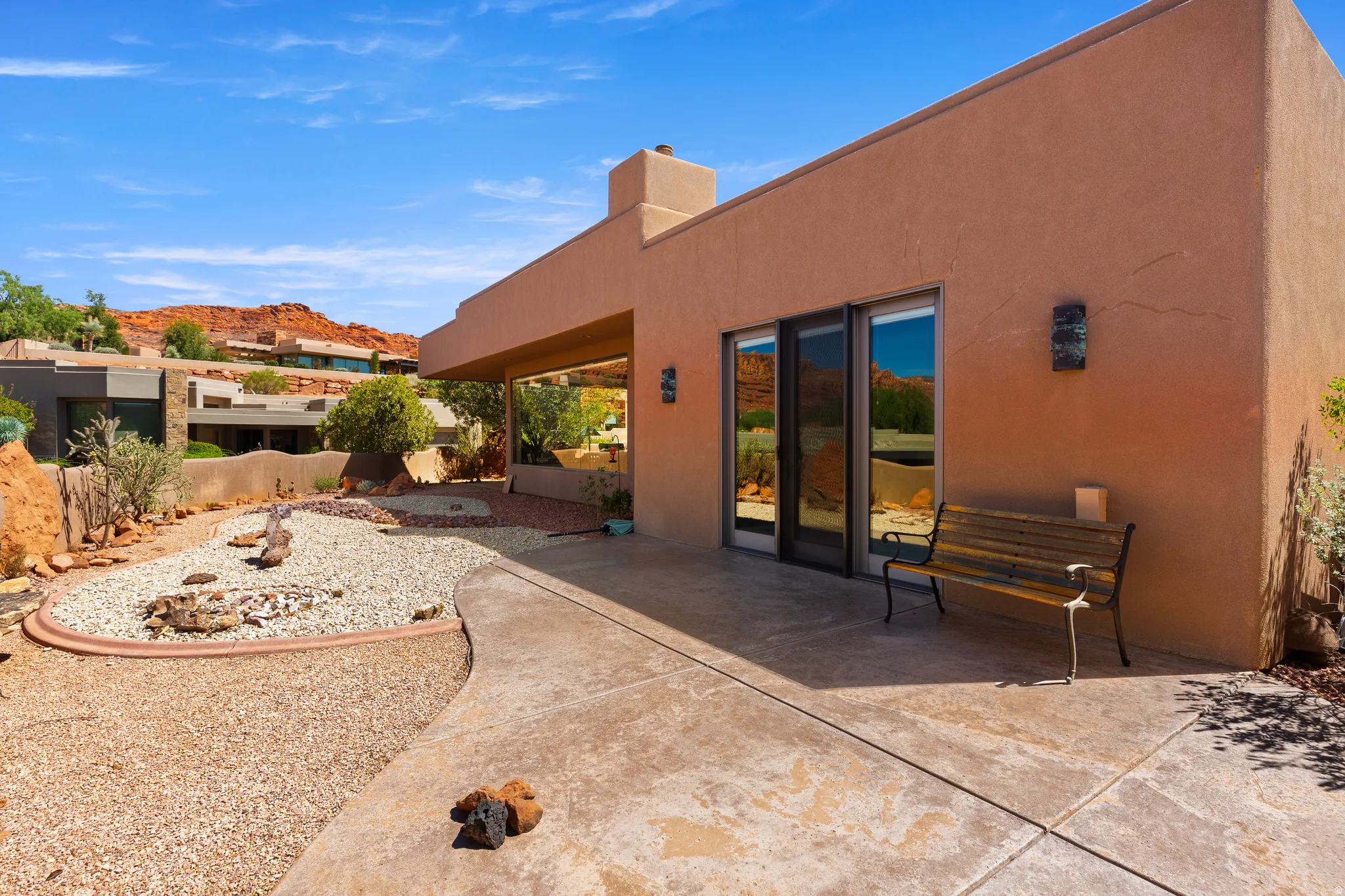 Stucco exterior with a covered patio, desert landscaping, and sliding glass doors