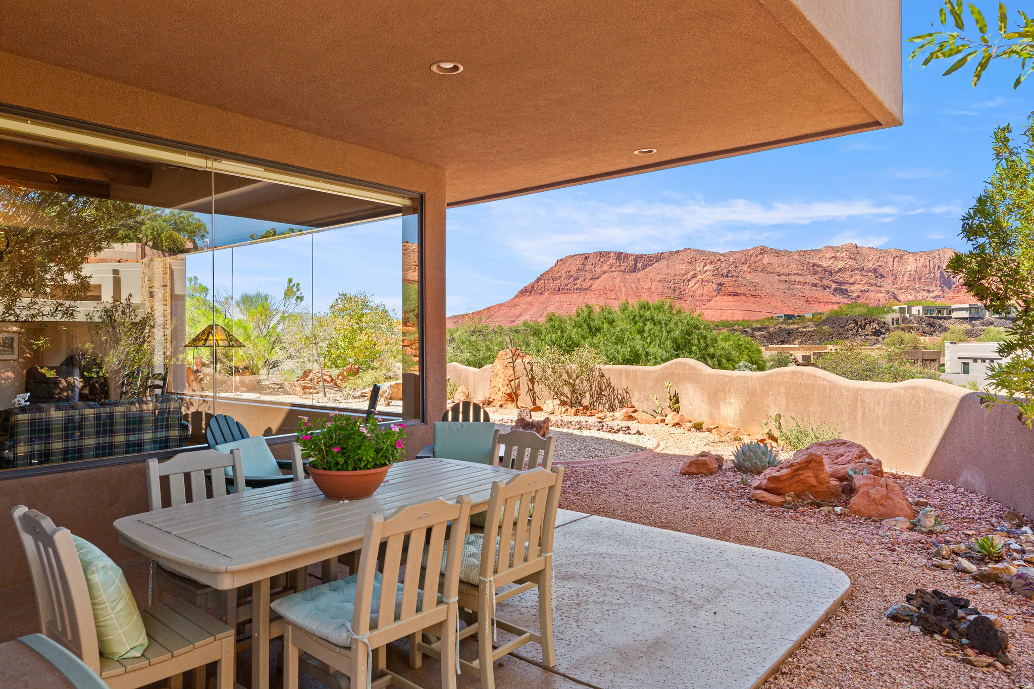 Covered patio with recessed lighting, large format sliding glass doors, and a desert-inspired landscape with natural rock formations