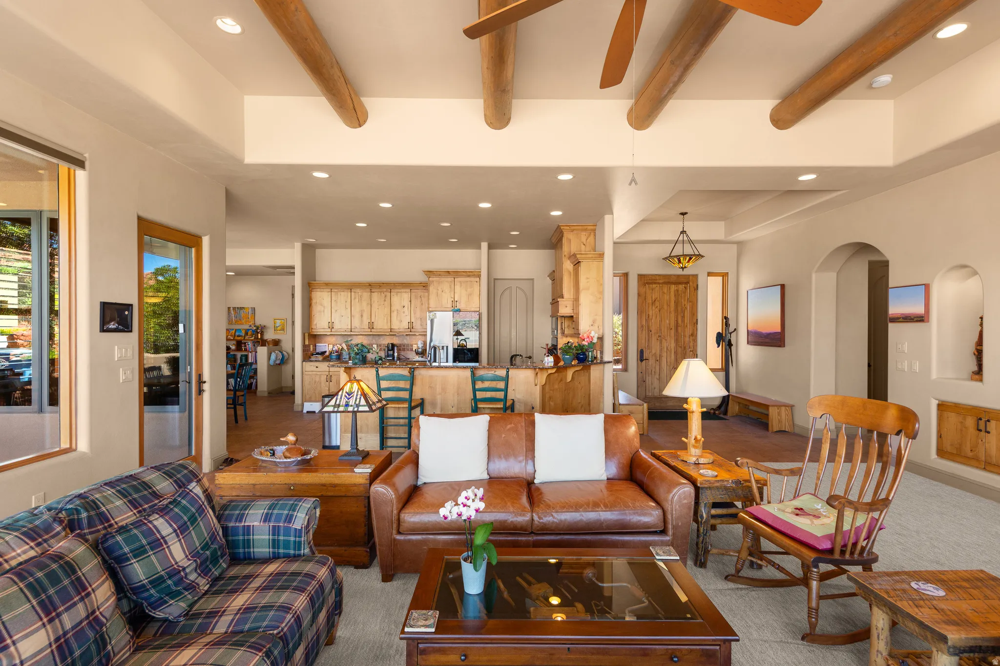 Open-concept living space with wood-beam ceiling accents, recessed lighting, and large windows