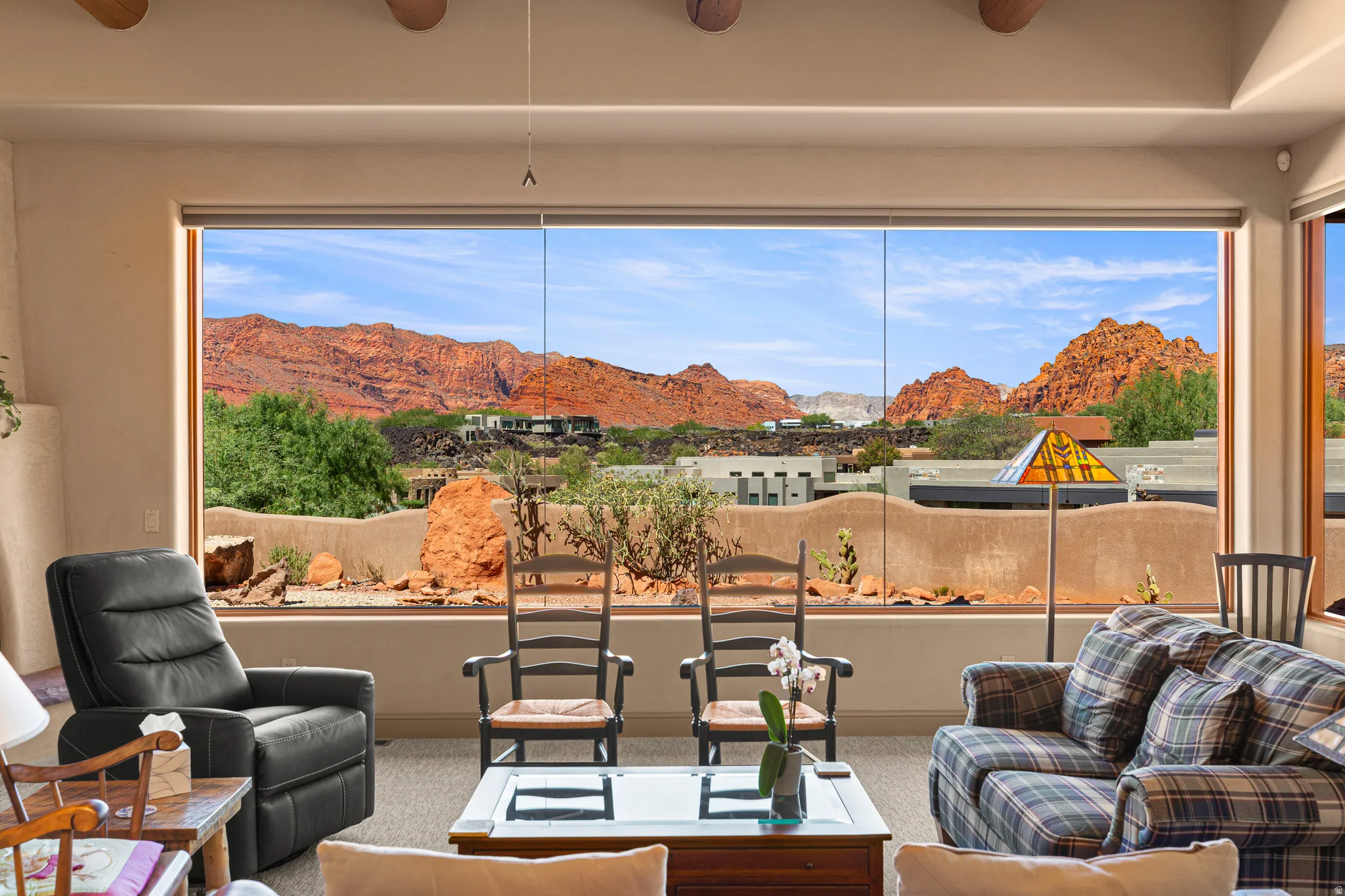 Expansive window wall with desert landscape, exposed wood ceiling beams, and a built-in recessed wall niche