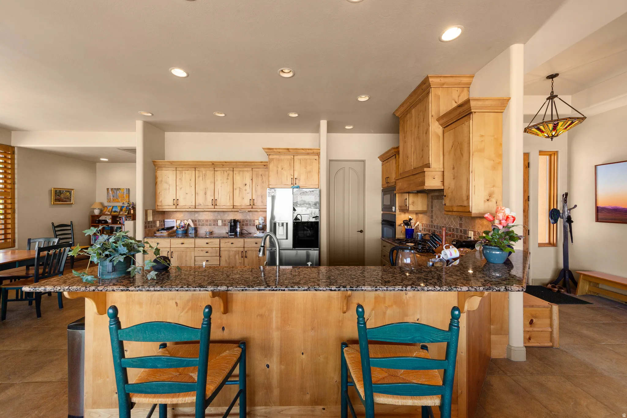 Kitchen featuring wood cabinetry, granite countertops, tile backsplash, and stainless steel appliances