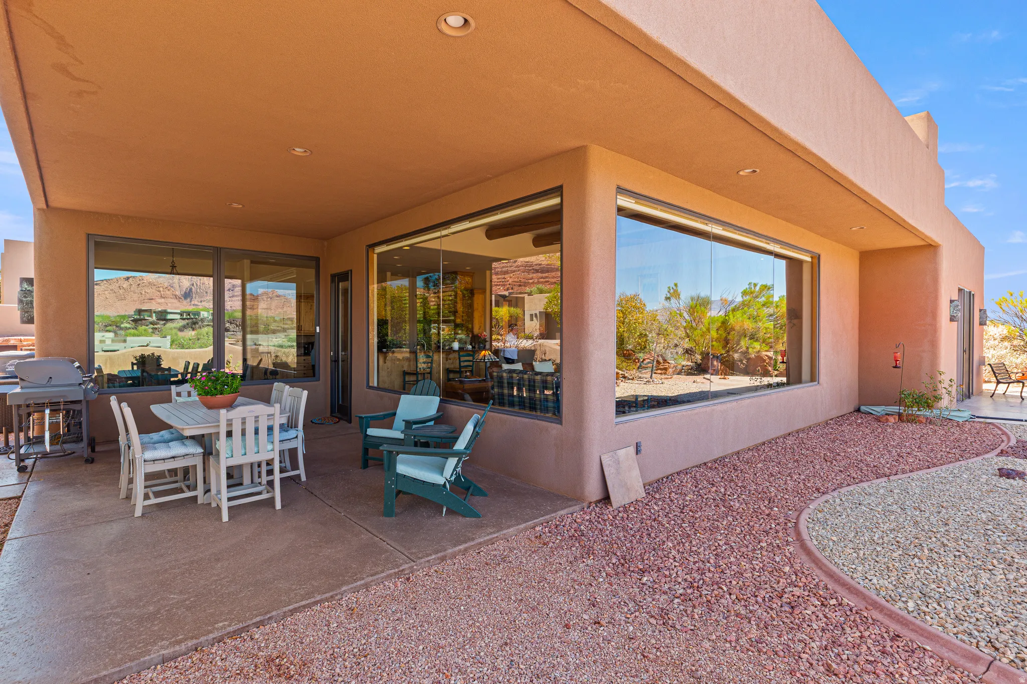 Expansive covered patio with recessed lighting, large picture windows, and desert-inspired landscaping