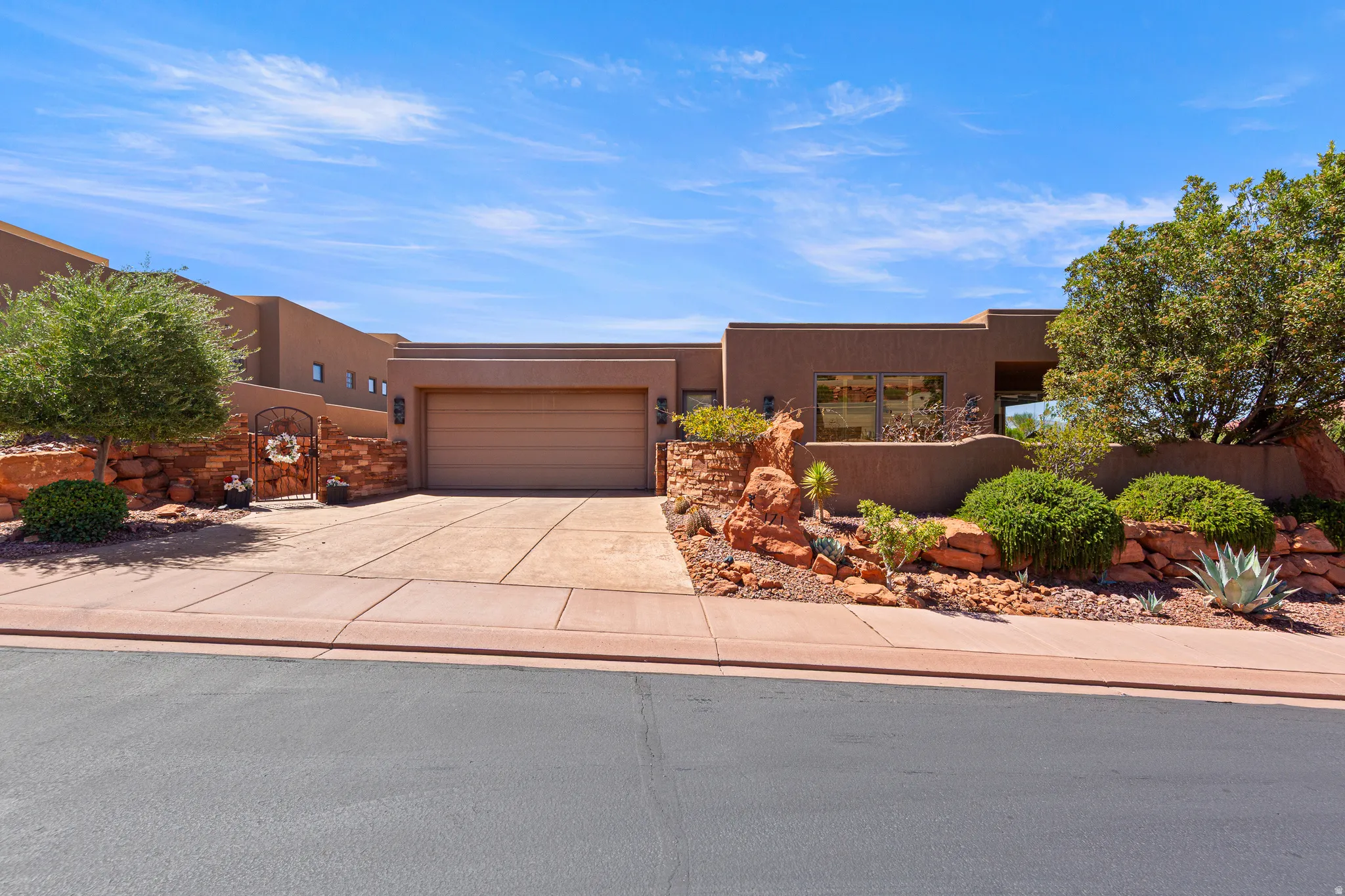 Stucco exterior with a flat roofline, integrated garage, and stone wall accents