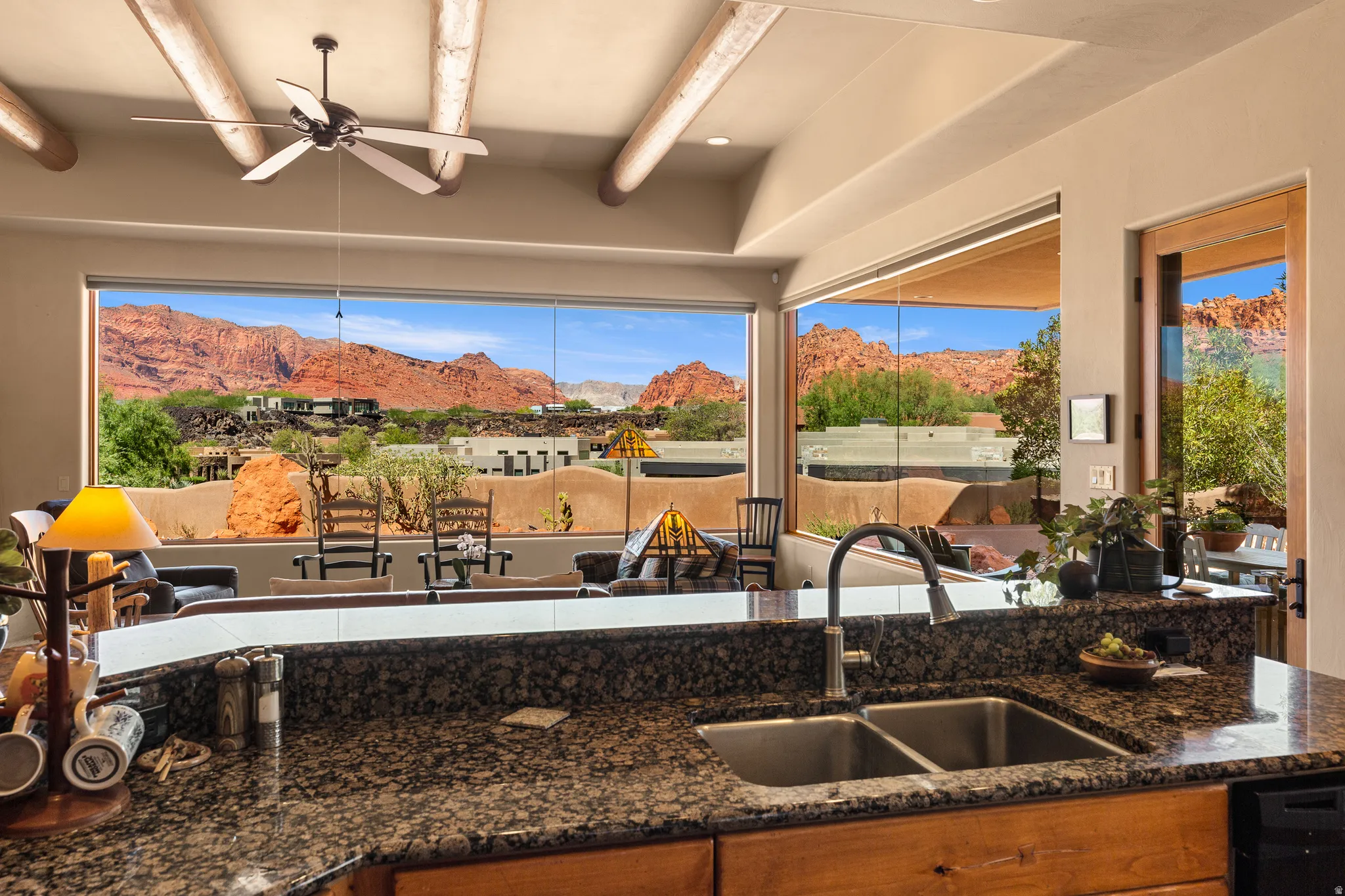 Kitchen featuring a double basin sink, granite-finish countertops, wood cabinetry, and a black ceiling fan