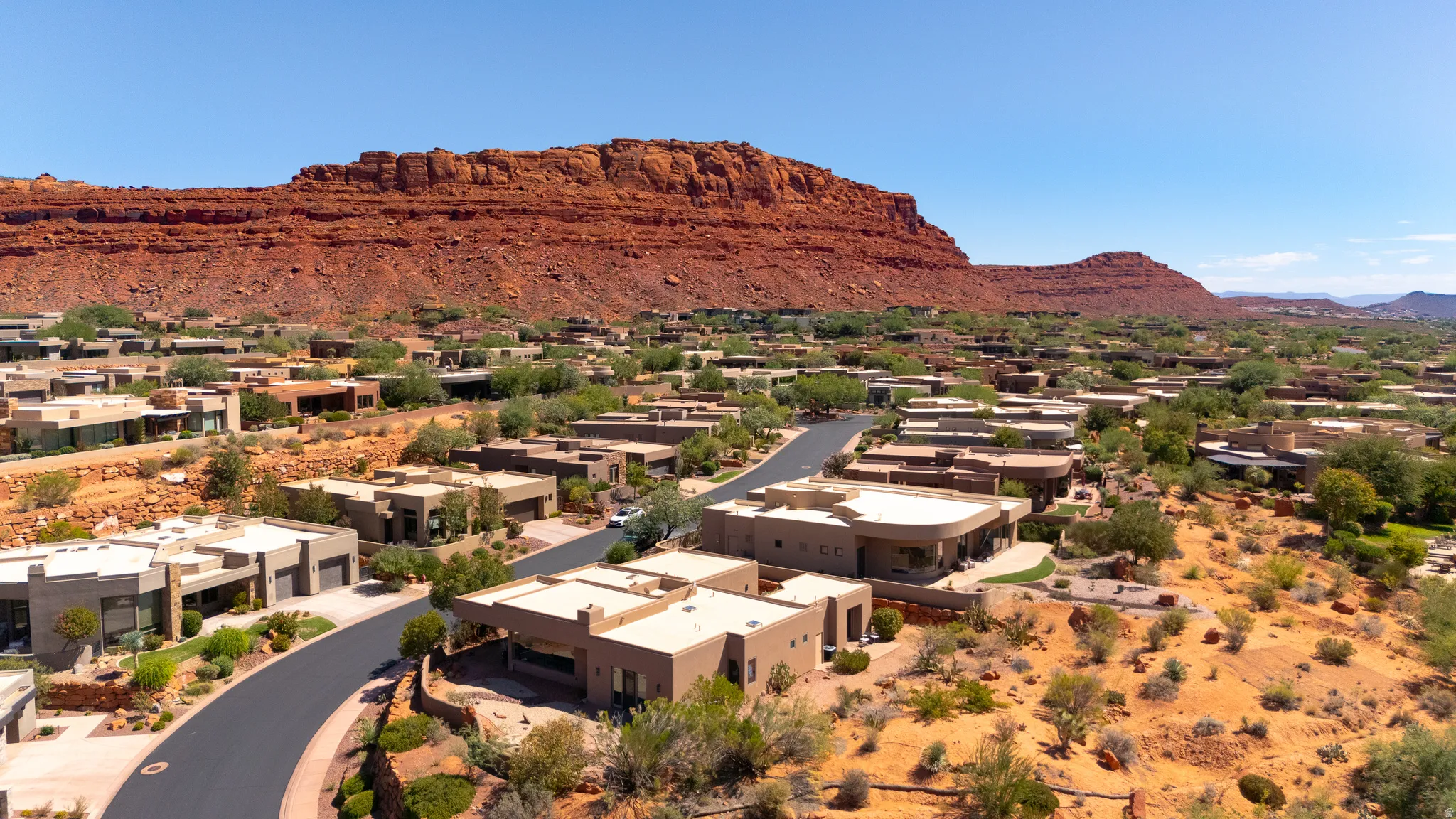 Residential community with desert landscaping and diverse architectural styles set against a prominent red rock formation