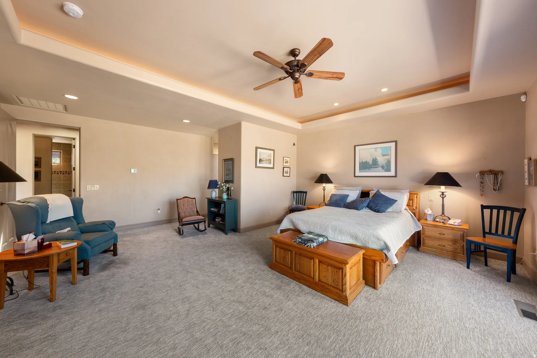 Recessed lighting, wood-blade ceiling fan, tray ceiling with cove lighting, warm neutral wall tones, and plush carpeting