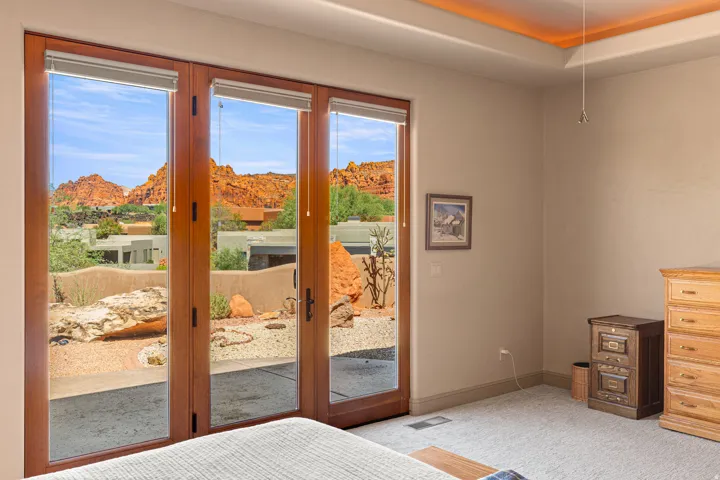 Wood-frame patio doors with roller shades, tray ceiling with cove lighting, and neutral wall tones