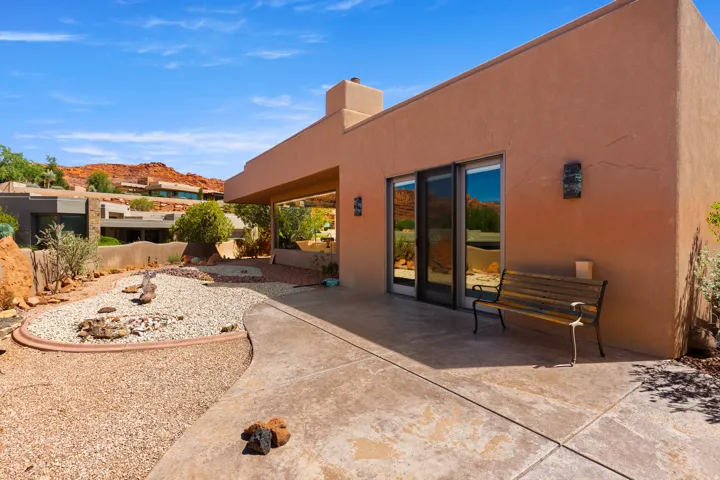Stucco exterior with a covered patio, desert landscaping, and sliding glass doors