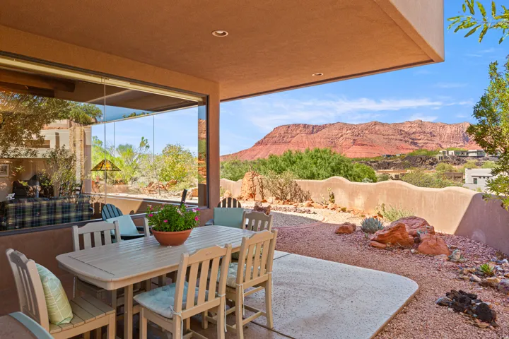 Covered patio with recessed lighting, large format sliding glass doors, and a desert-inspired landscape with natural rock formations