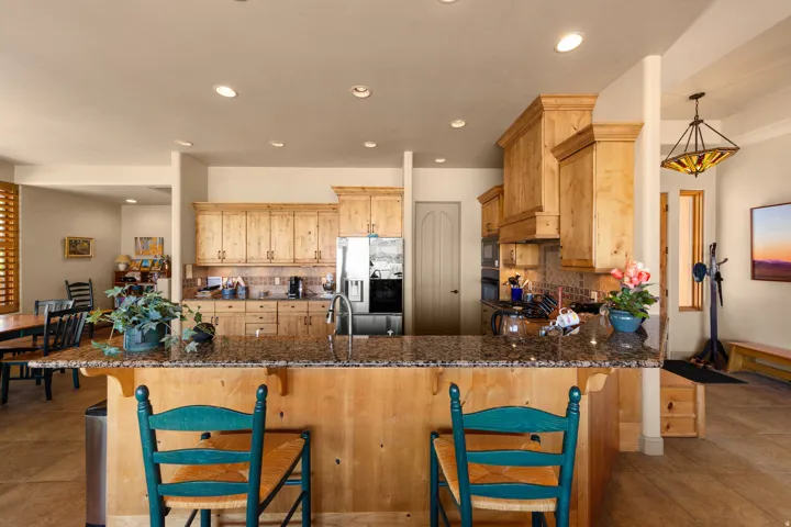 Kitchen featuring wood cabinetry, granite countertops, tile backsplash, and stainless steel appliances