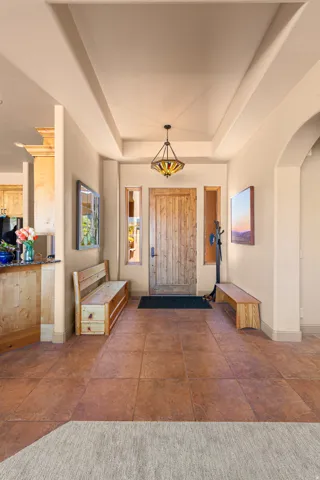Entryway featuring a tray ceiling, a decorative pendant light fixture, a distressed wood-paneled door, and large square floor tiles