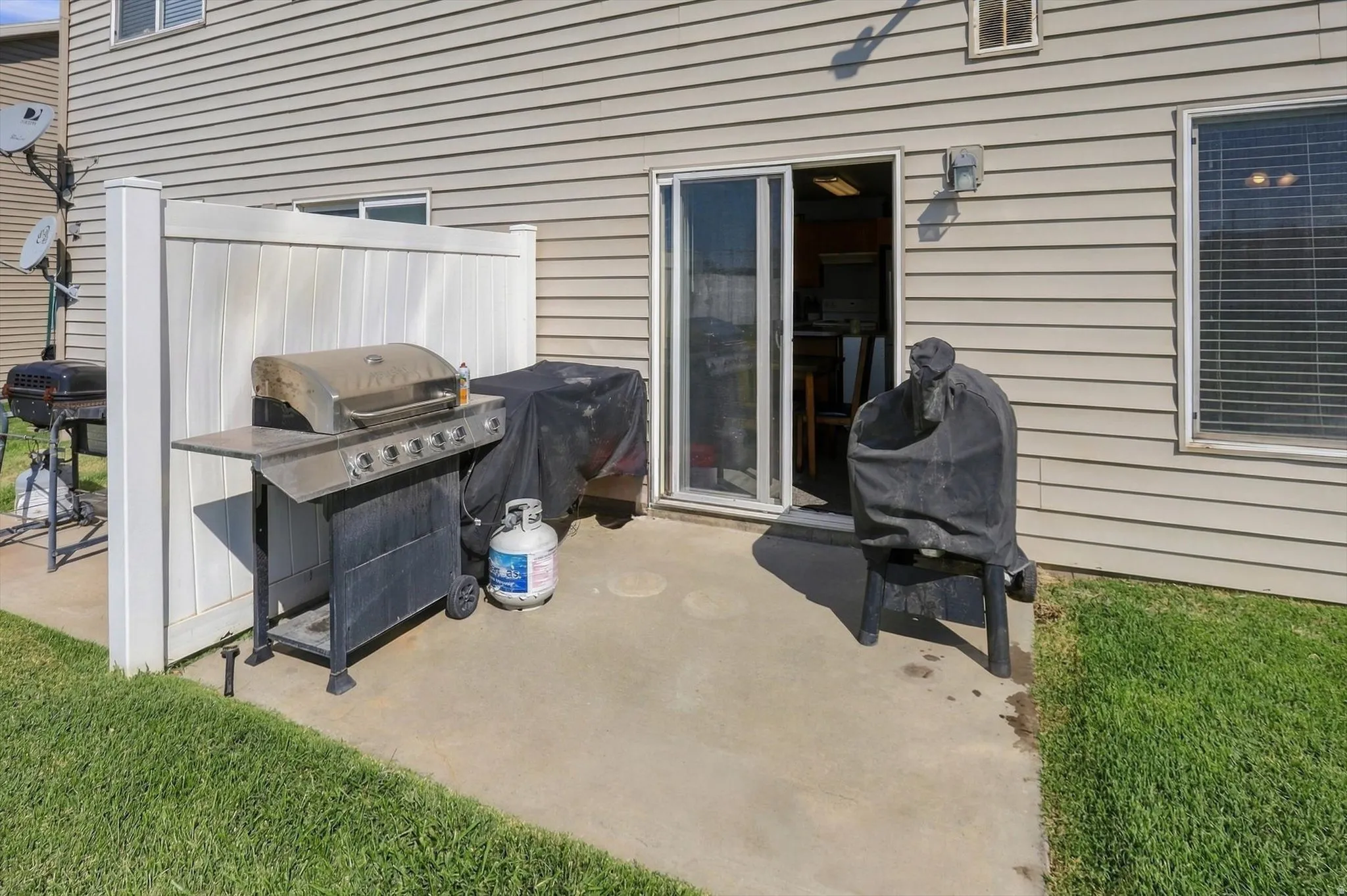 Concrete patio with a privacy wall, exterior siding, and a sliding glass door