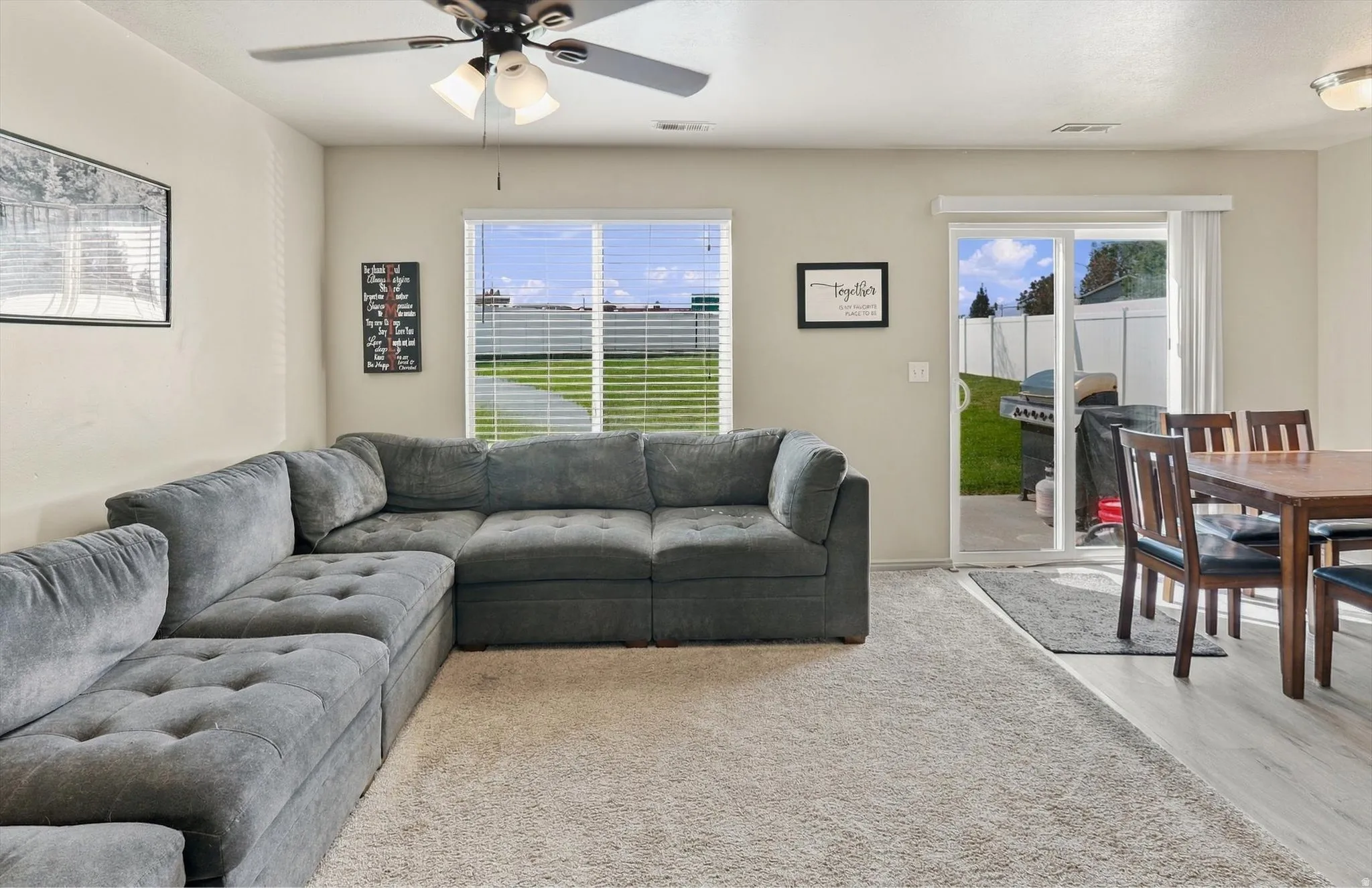 Living area featuring a ceiling fan, window with horizontal blinds, and carpet flooring