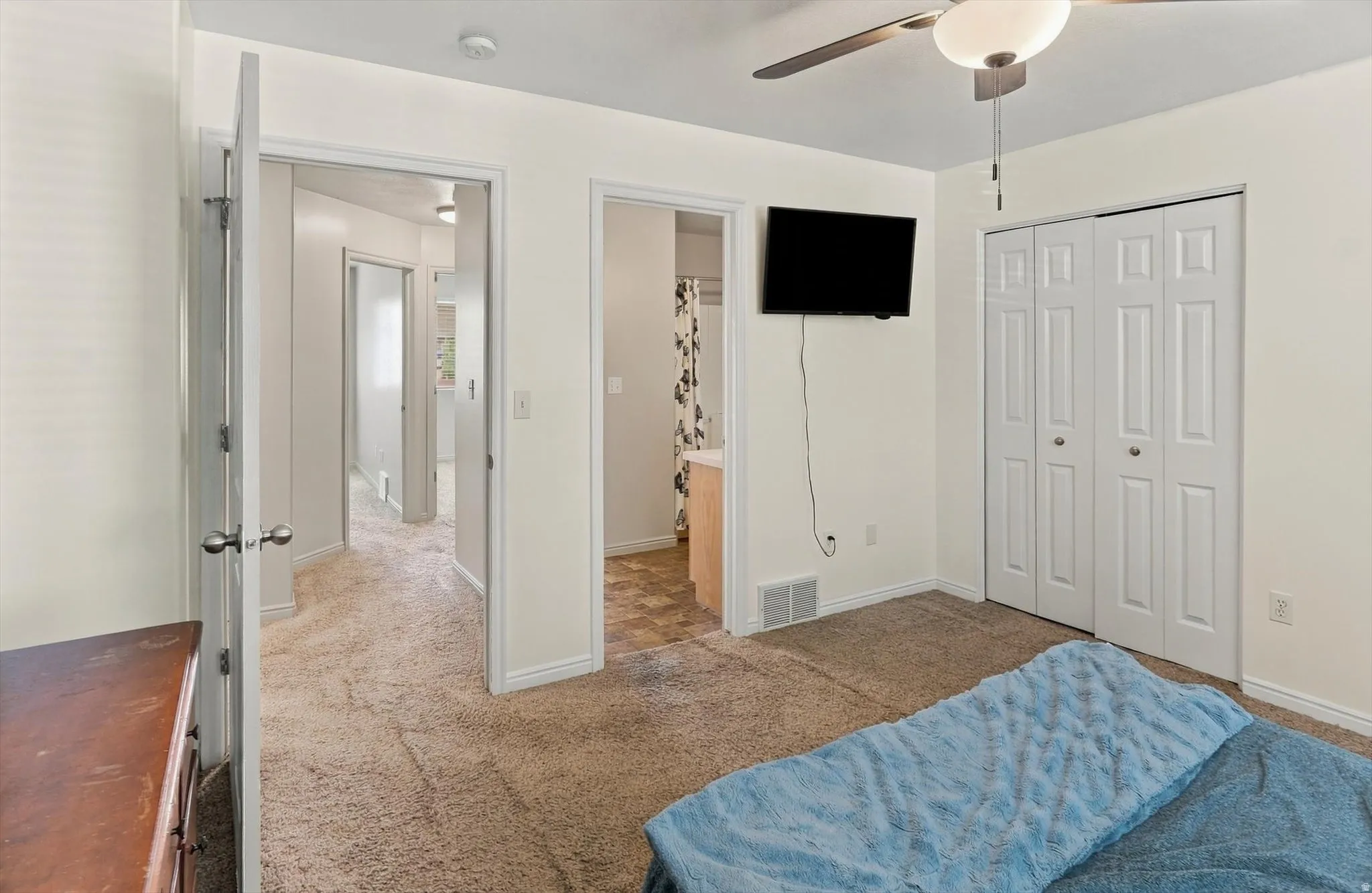 Plush carpeting, bi-fold closet doors, and an overhead ceiling fan with lighting
